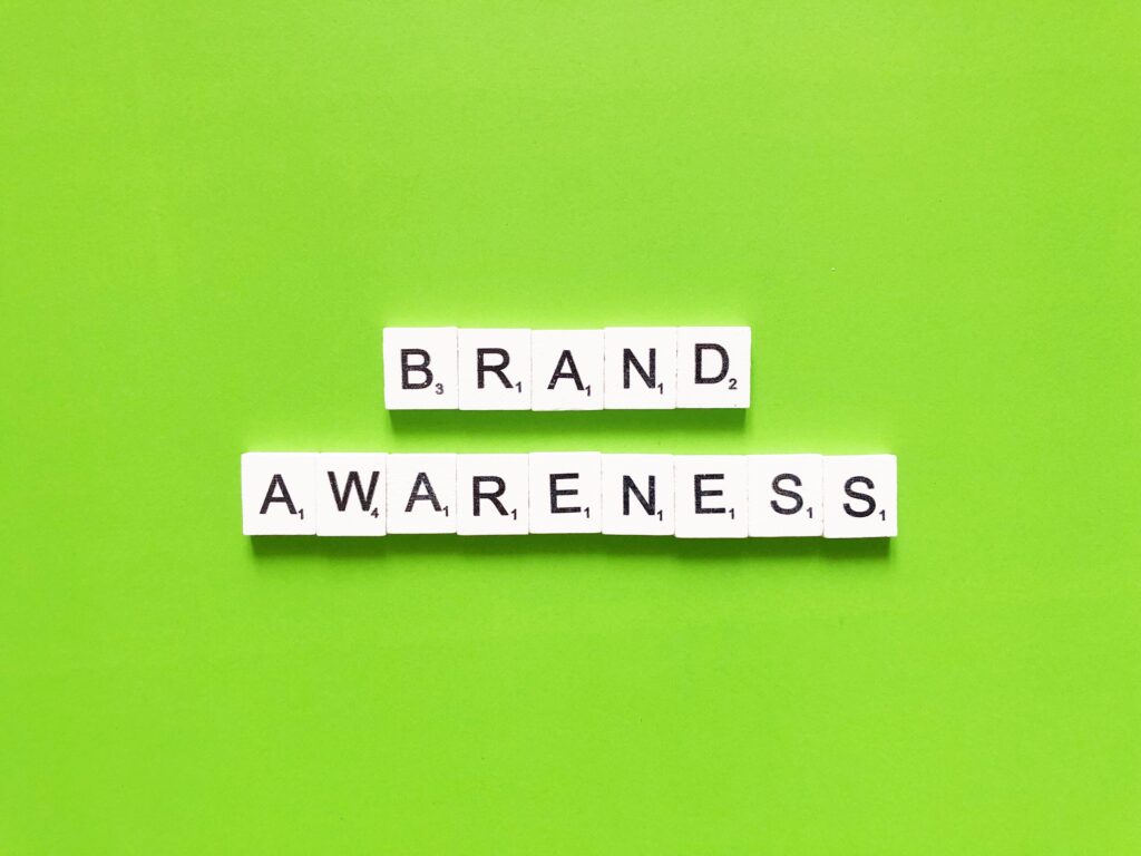 Square tile letters spell out "brand awareness" against a vibrant green background.